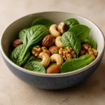 A bowl of mixed nuts and fresh spinach - illustration for Best Foods for Healthy Hair Growth and Strong Hair