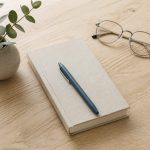 Desk with notebook pen and eyeglasses on wood - illustration for 10 steps to create a strong academic and career plan before college