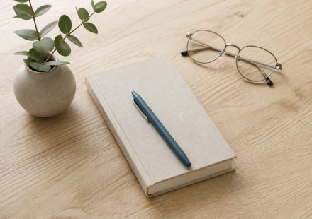Desk with notebook pen and eyeglasses on wood - illustration for 10 steps to create a strong academic and career plan before college