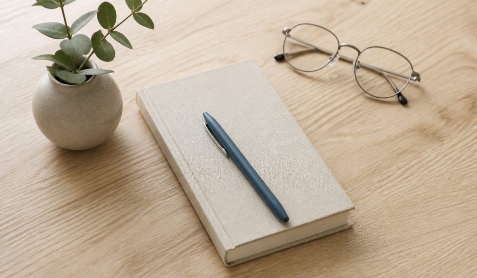 Desk with notebook pen and eyeglasses on wood - illustration for 10 steps to create a strong academic and career plan before college