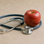 Stethoscope resting next to red apple - illustration for Discover the most important heart health tests men should undergo after age 40