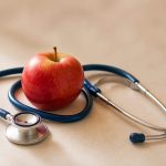Stethoscope resting beside a red apple - illustration for Heart Disease: When to Get Checked at a Clinic