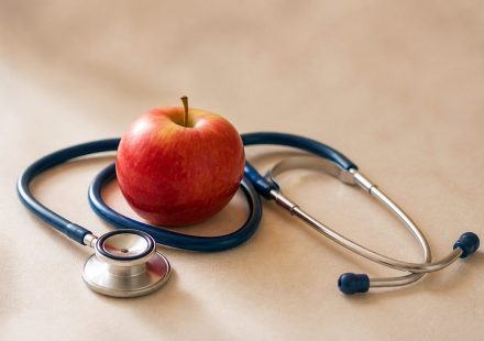 Stethoscope resting beside a red apple - illustration for Heart Disease: When to Get Checked at a Clinic