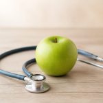 Green apple with stethoscope on wooden table - illustration for How Preventive Healthcare Can Improve Your Quality of Life