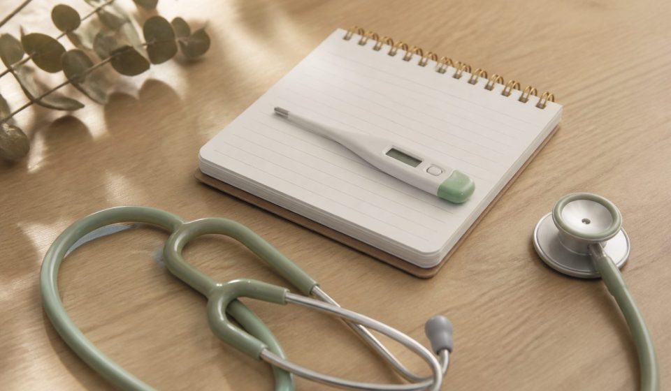 Stethoscope thermometer notepad on wooden table - illustration for how regular health checkups boost long-term wellness and prevention