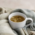 White ceramic mug with herbal tea and blanket - illustration for How proper rest boosts muscle repair and overall health