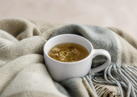 White ceramic mug with herbal tea and blanket - illustration for How proper rest boosts muscle repair and overall health