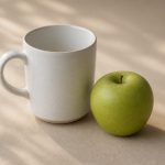 White ceramic mug and fresh green apple on table - illustration for Why your blood pressure readings matter at every checkup